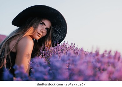 Woman lavender field. Happy carefree woman in black dress and hat with large brim smelling a blooming lavender on sunset. Perfect for inspirational and warm concepts in travel and wanderlust. Close up