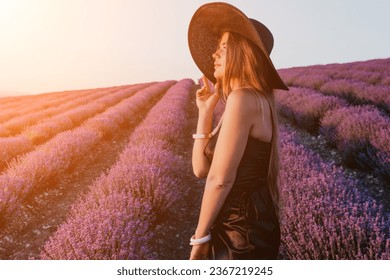 Woman lavender field. Happy carefree woman in black dress and hat with large brim walking in a lavender field during sunset. Perfect for inspirational and warm concepts in travel and wanderlust. - Shutterstock ID 2367219245