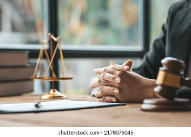 A Woman Lawyer Sits In The Office Of Her Law Firm, On A Table With A Scale Of Justice And A Hammer Laying Down, She Is An Attorney Serving His Client. Lawyer Concepts And Lawful Justice.