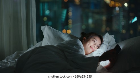 Woman lay down on bed and use of mobile phone at night