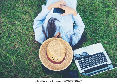 Woman Lay Down Sleep On Green Grass Meadow Garden Summer Sunshine Day Happy Time Outside. Hipster Freelance Work On Laptop Use Hat Cover Face Sleep On Grass Field. Relax Woman Lying Down Green Garden