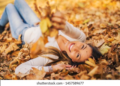 Woman laying down on the pile of leafs and playing