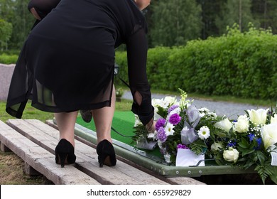 Woman laying flowers on a grave at a funeral