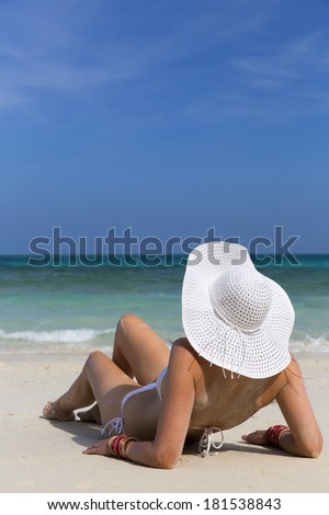 Woman laying on beach enjoying summer holidays looking at the ocean.