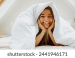 A woman lays in bed under a white blanket, smiling and feeling comfortable