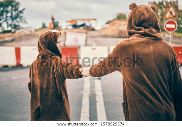 woman leads a man\'s hand forward.\
guy and girl in bear costumes. concept of love, care and\
wear