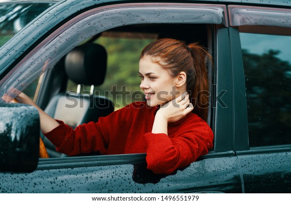 The woman leaned on the open window in\
the car and sits behind the wheel side\
view