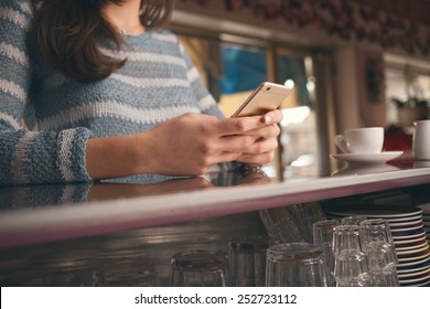 Woman Leaning On The Bar Counter And Text Messaging With Her Mobile, Hands Close Up