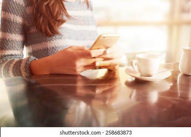 Woman leaning on the bar counter and text messaging with her mobile, hands close up - Powered by Shutterstock