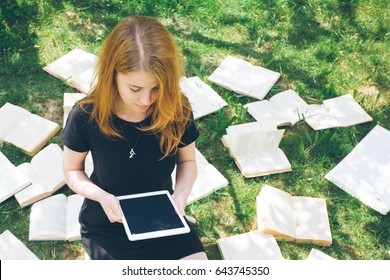 Woman learning with ebook reader and book. Choice between modern educational technology and traditional way method. Contemporary education. Girl in the summer garden