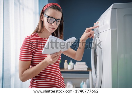 Woman learning how to use her washing machine and fixing problems, she is checking the instructions on the manual