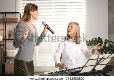 Woman learning to sing while her teacher accompanying on piano indoors