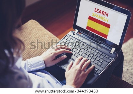 Woman learning Spanish language through internet with a laptop at home