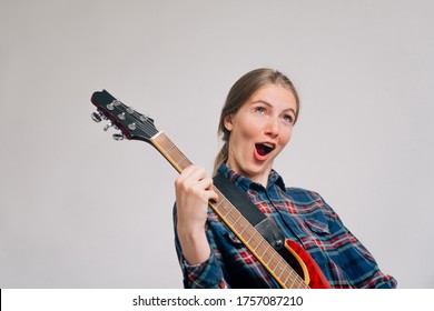A woman learns to play the electronic guitar. A young rocker plays a musical instrument. Screaming during a song.