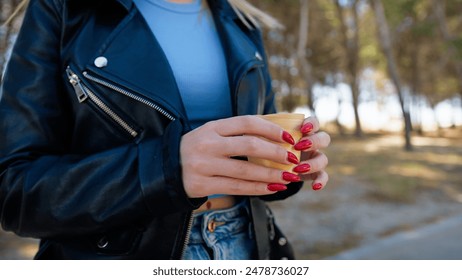 Woman with leather jacket holds a cup of coffee