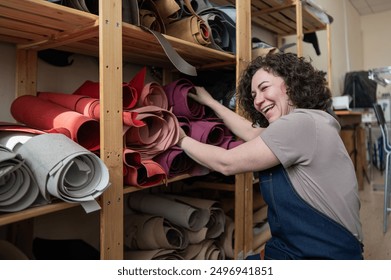 Woman leatherworker selects a roll of leather in the workshop.  - Powered by Shutterstock