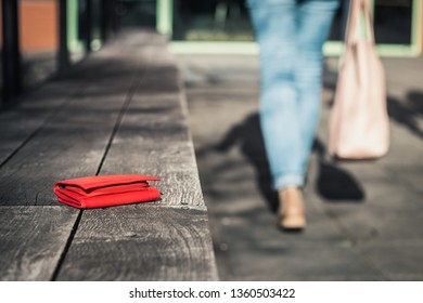 Woman is leaving from a bench where she forgot her leather wallet. Lost purse on city street