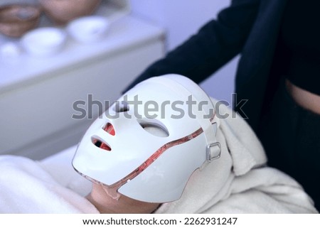 Woman with led light therapy facial and neck beauty mask photon therapy