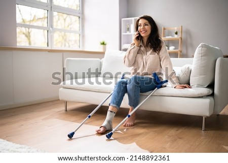 Woman With Leg Injury Using Crutches At Home