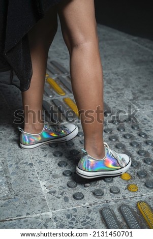 Woman leg with Metallic sneakers shoes, white shoelaces on street