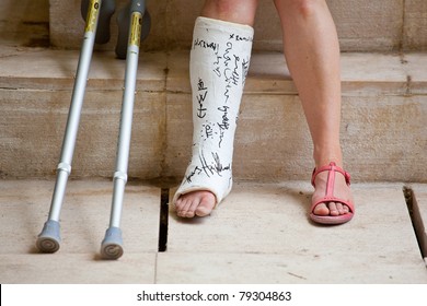 A Woman With Leg In Plaster And Crutches