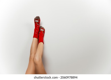 Woman Leg In Red Christmas Socks On Gray Isolated Background