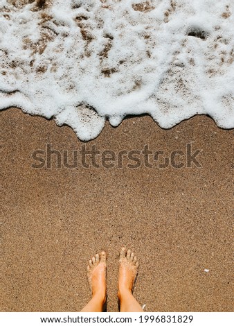 Woman legs barefoot at sea foam waves on sand beach summer day. top view above women feet. Ocean clear water seafoam. girl on beach Summer background nature concept holiday vacation. top sea wallpaper