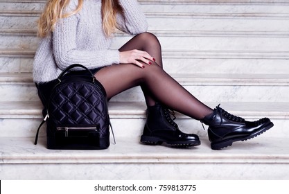 Woman legs in black ankle boots with bag. Trendy hipster outfit style