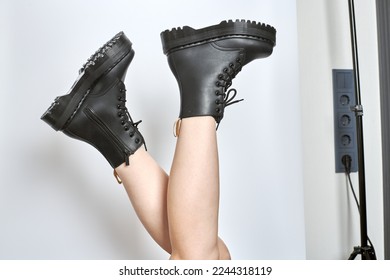 Woman legs in black combat boots on high heel platform with lug soles upside down side view on isolated white background. Female legs wear military fashionable high heel platform combat boots - Powered by Shutterstock