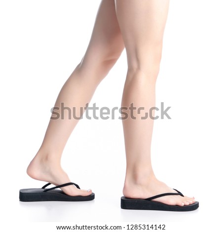 Woman legs in black flip flops goes on white background isolation