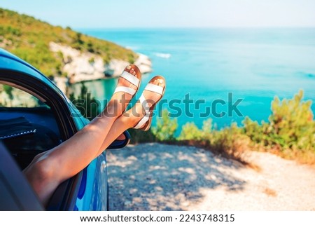 Woman legs by blue sea background in car. Summer vacations concept with free woman enjoying freedom