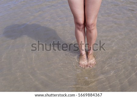 Woman legs dipped in sea water.