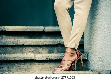 woman legs in high heel golden sandals stand on stairs, outdoor shot