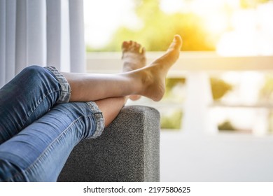 Woman legs on the sofa couch. Woman feet up against window. Woman lying on the bed with raised legs up, against the open balcony
