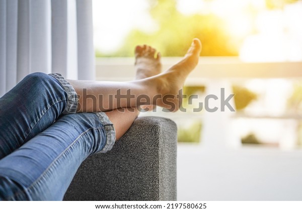Woman legs on the sofa couch. Woman feet up\
against window. Woman lying on the bed with raised legs up, against\
the open balcony