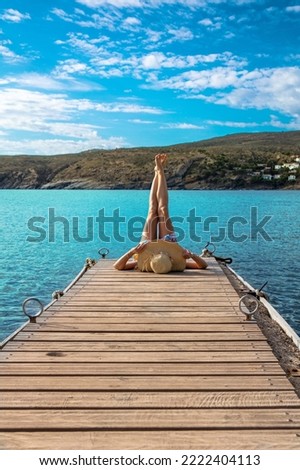 Woman legs up on wooden pier in front of turquoise sea ( relax, freedom, vacation concept)