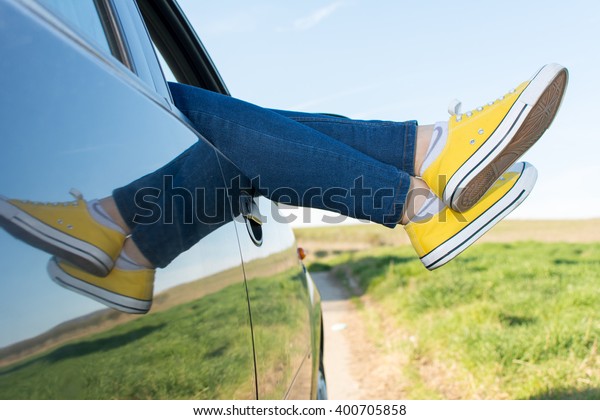 Woman legs out\
of the car window. Travel and\
fun