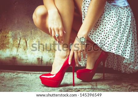 woman legs in red high heel shoes and short skirt outdoor shot against old metal door