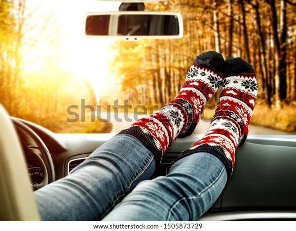 Woman legs with socks in cark\
interior and autumn road background. Free space for your text.\
