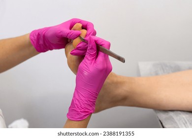 Woman legs In a Spa Salon Receiving pedicure of feet with a blunt knife. Legs And Nail Skin Care. Pedicure Procedures And SPA. Close up, Selective Focus.