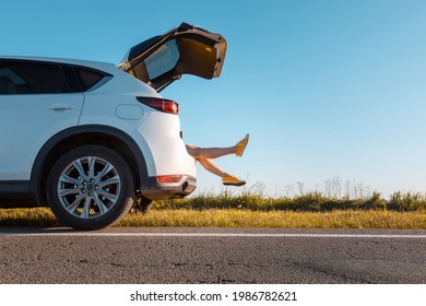 Woman Legs Stick Out Of Suv Car Trunk Parked At Roadside Of Speedway Copy Space