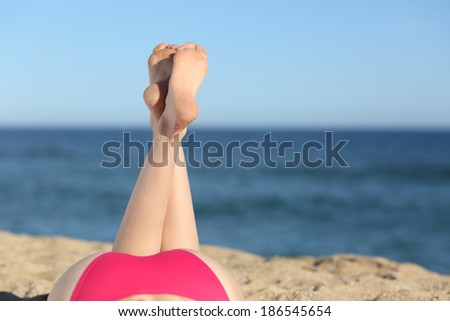 Woman legs sunbathing on the beach lying down with the horizon in the background                