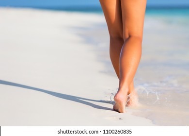 Woman Legs Walking On The Beach Sand