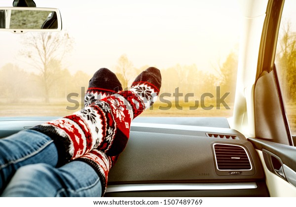 Woman legs with warm socks\
and car interior with autumn landscape. Free space for your\
decoration. 