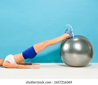 Woman Lied Down Doing Hamstring Curl Exercise With A Stability Ball. A Work Out That Strengthen The Hamstrings And Glutes.