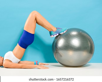 Woman lied down doing hamstring curl exercise with a stability ball. A  work out that strengthen the hamstrings and glutes. - Powered by Shutterstock
