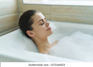 Woman Lies In Bathtub With White Foam Wet Hair Relaxing