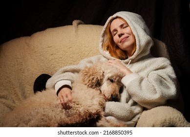 Woman Lies With A Large Dog On The Couch. The Shaggy Domestic Dog Laid Its Head. The Relationship Of Animals And People At Home.