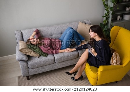 a woman lies on the couch and communicates with a psychologist with a woman in an armchair. Methods of psychoanalysis