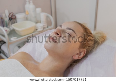 A woman lies on a couch waiting for a procedure in a beauty parlor.